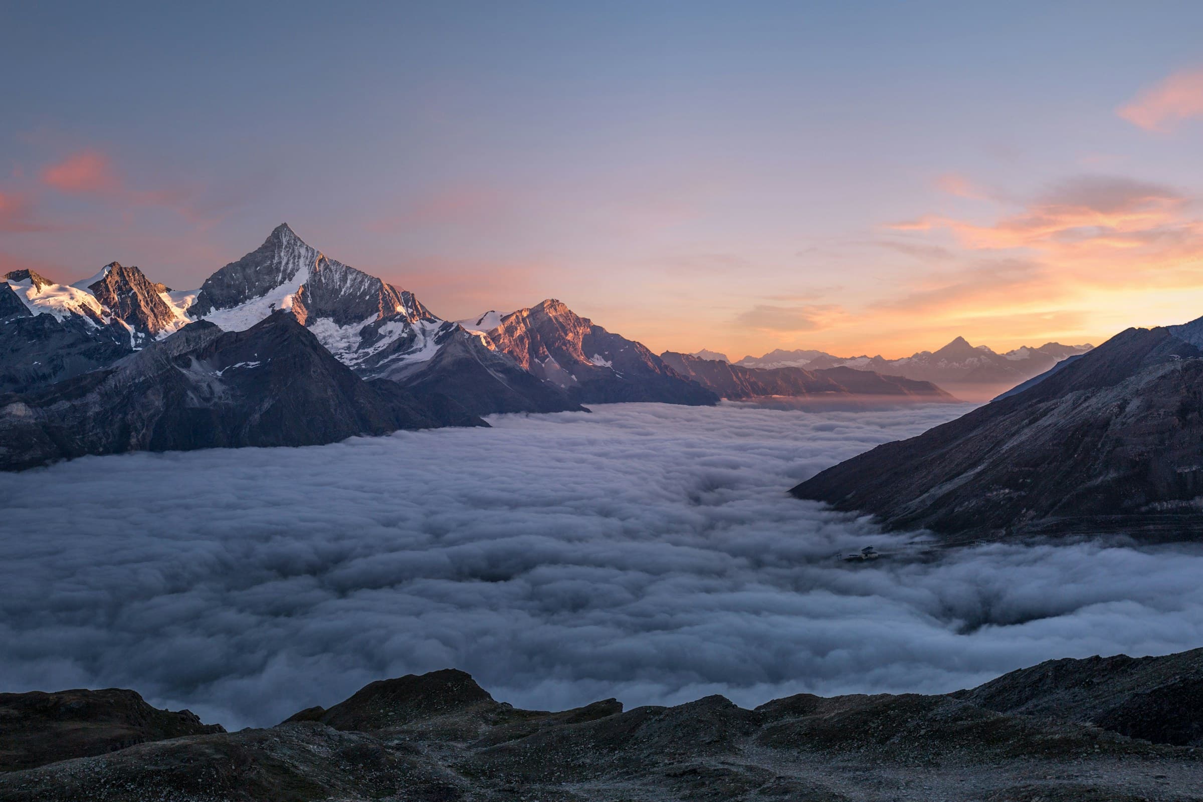 Snow-covered mountain peaks rising through cloud