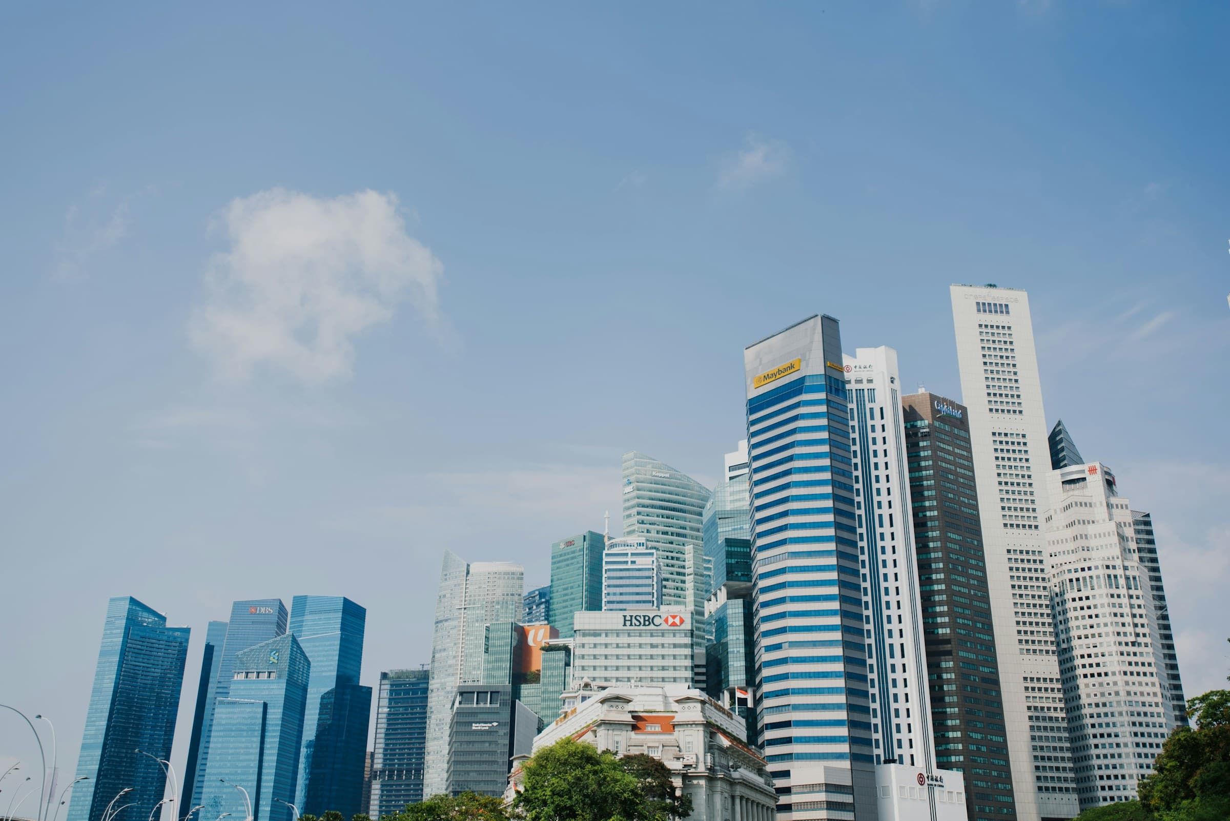 Low-angle view of Singapore's central business district towers against a pale blue sky